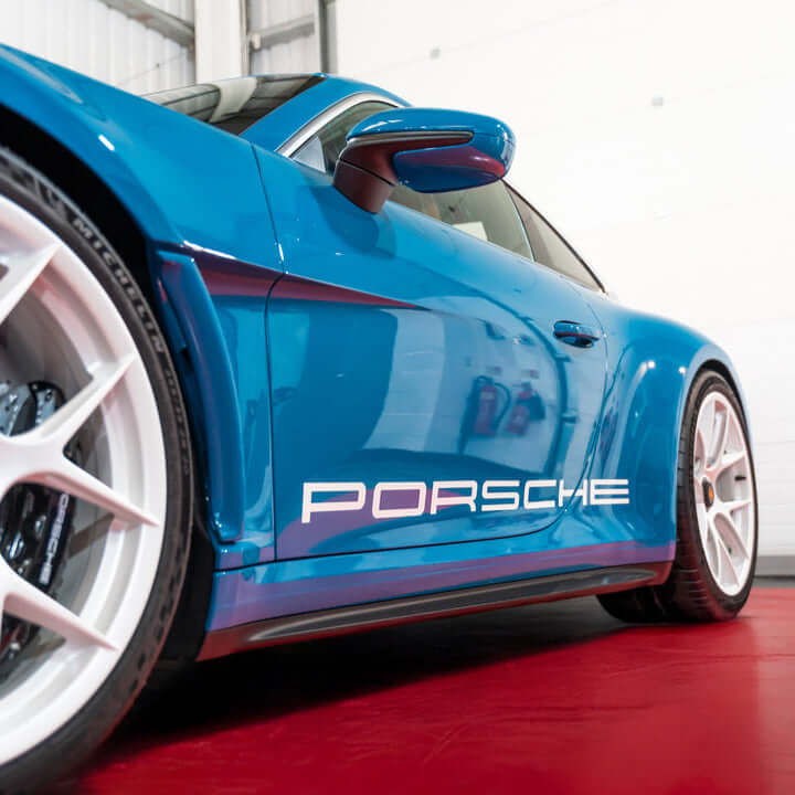 Blue Porsche car side view in a garage