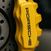 Close-up of a yellow Porsche brake caliper on a dark background