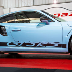 Blue sports car with 'GT3RS' decal on a red carpet indoors