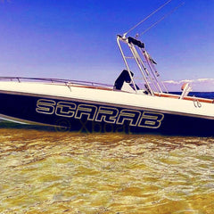 Boat named 'Scarab' on a clear day with blue sky and clear water.