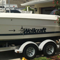 Wellcraft boat on a trailer in front of a house with trees in the background