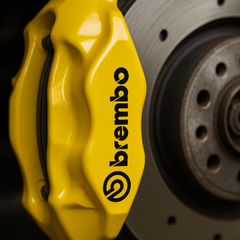 Close-up of a yellow Brembo brake caliper on a car rotor.