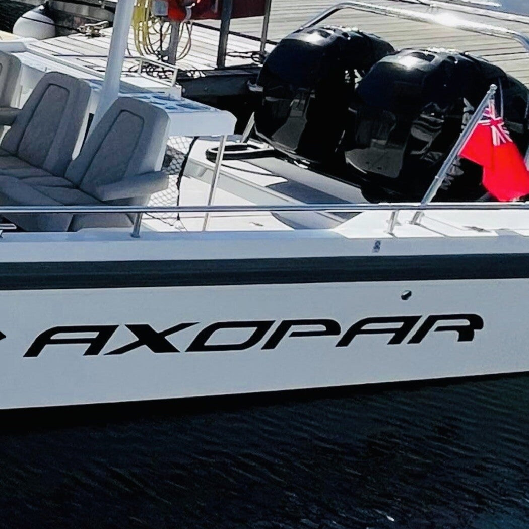 White boat with 'Axopar' branding on a dock with other boats in the background.