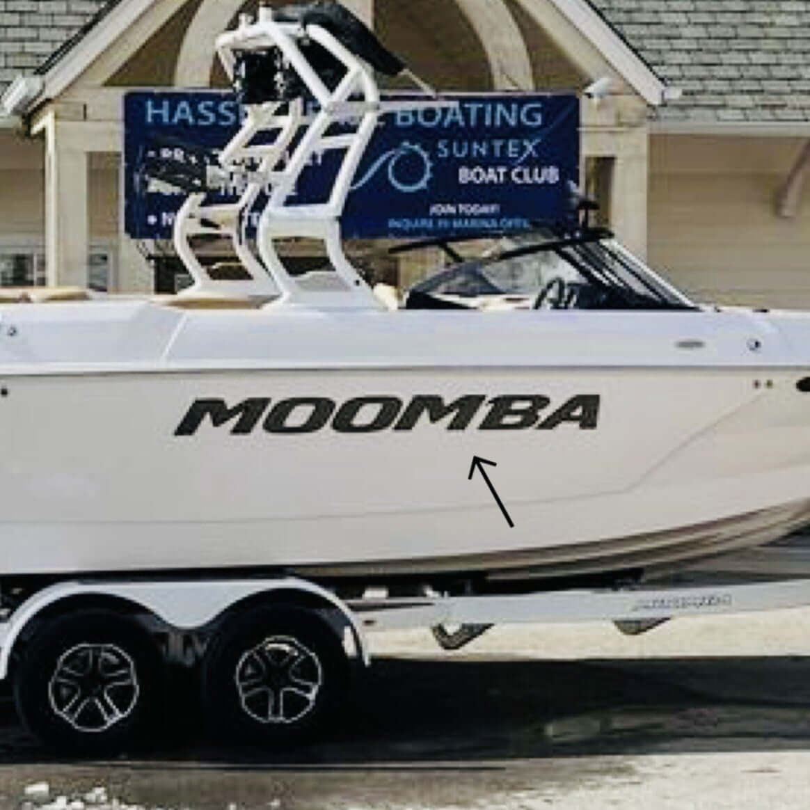 White Moomba boat on a trailer in front of a building with a sign for Hassett Boating Suntex Boat Club.