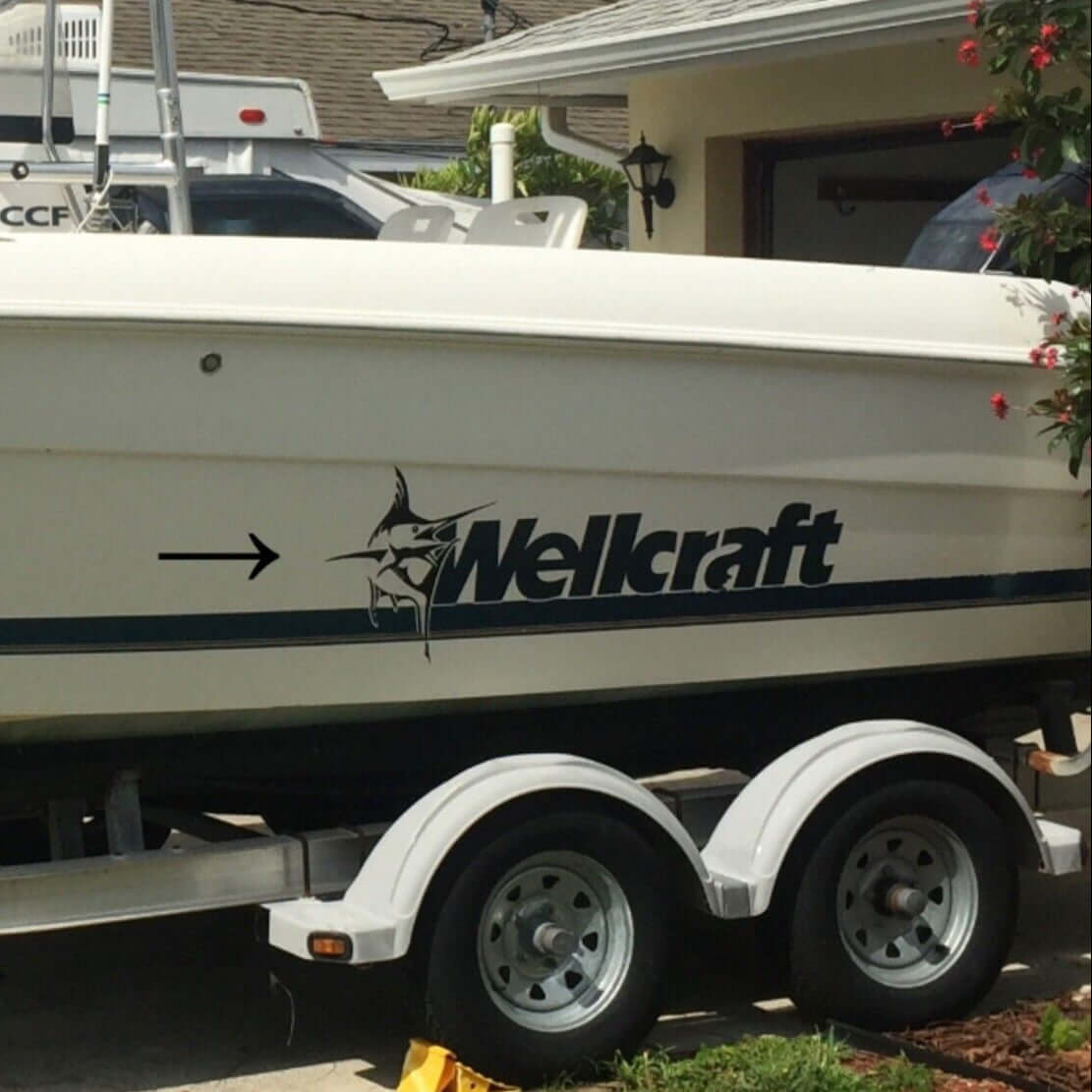 Wellcraft boat on a trailer in front of a house with trees in the background